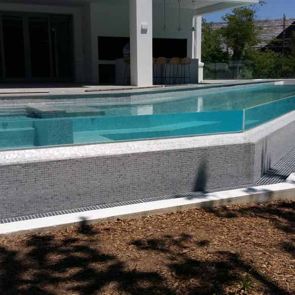 Fully tiled rimflow pool with in floor cleaning system, Plexiglass window and Plexiglass rimflow edge.